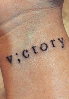 a wrist tattoo with the word victory written in cursive font on it's side