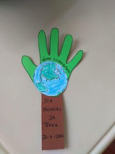 a hand made out of paper with the earth on it