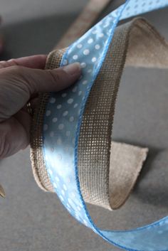 a person is holding a blue ribbon with white polka dots on it and there are other items in the background