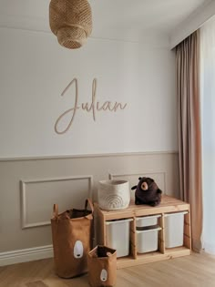 a room with white walls and wooden flooring is decorated in neutral colors, including the name julian on the wall