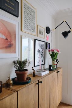 a room with pictures, flowers and plants on the side of the wall in front of it