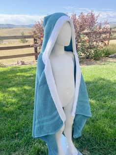 a white mannequin with a blue towel wrapped around it's head in the grass