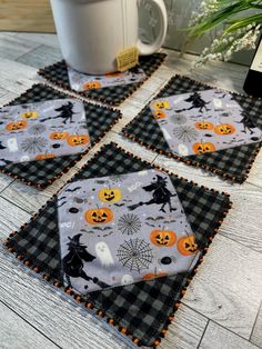 four halloween coasters sitting on top of a wooden table next to a coffee cup