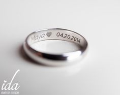 a wedding ring with the names of two people engraved on it, sitting on a white surface