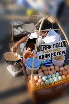 a man selling eggs from a cart on the side of the road with a sign that reads kerak telora