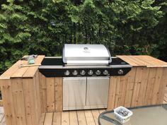 an outdoor kitchen with grill and table on deck