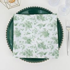 a green plate topped with a napkin next to a fork and knife on top of a table