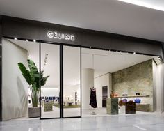 a woman is standing in the doorway of a clothing store that has glass doors on both sides