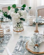 the table is set with white flowers and silverware