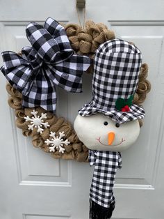 a snowman wreath hanging on the front door with a black and white plaid bow