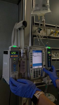 a person in blue gloves is operating an automated machine with two monitors on each side