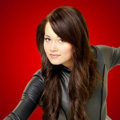 a woman with long brown hair and black leather gloves on her shoulder posing for the camera