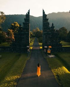 a woman in an orange dress walking down a road