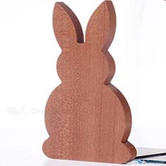 a wooden bunny sitting on top of a table next to a pen and pencil holder