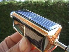 a solar powered device is being held up by someone's hand with a string attached to it