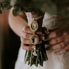 a close up of a person holding a bouquet and brooch on their wedding day