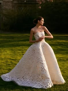 a woman in a wedding dress standing on the grass with her hand on her hip