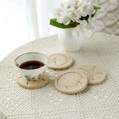 there are four coasters on the table with a cup of coffee and some flowers