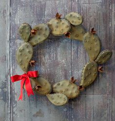 a wreath made out of cacti with a red ribbon around it on a wooden door