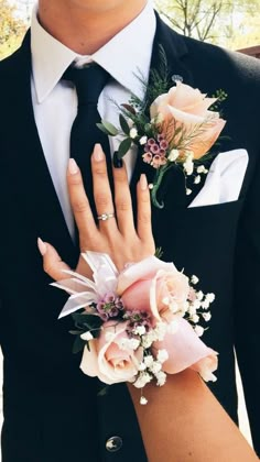 a close up of a person wearing a suit and tie with flowers on his lapel