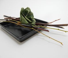 a small black plate with flowers on it and some stems sticking out of the top