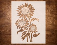 a stencil depicting three sunflowers on a wooden surface