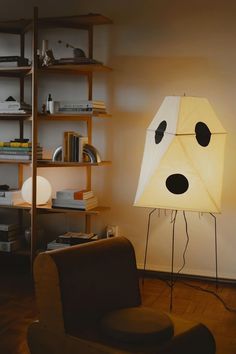 a lamp that has a dog face on it next to a chair and bookshelf