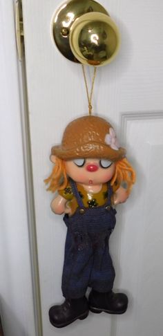 a door handle with a doll hanging from it's side and a bell attached to it