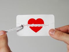 a person holding a piece of paper with a heart cut in half on top of it