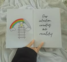 two children's hand holding open notebooks with writing on them and an image of a rainbow