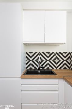 a kitchen with black and white tiles on the backsplash, counter tops and cabinets