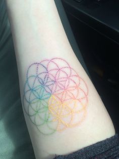 a person with a tattoo on their arm that has colored circles in the shape of a flower