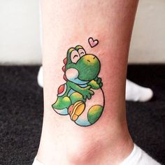 a small tattoo on the ankle of a person with a green and yellow cartoon character