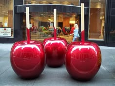 two large red apples sitting on top of each other in front of a store window