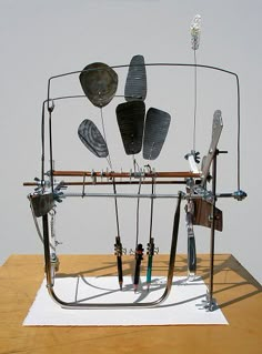 a metal sculpture on top of a wooden table next to a white wall and floor