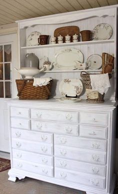 a white china cabinet with dishes on it