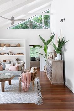 a living room filled with furniture and lots of plants on top of it's shelves