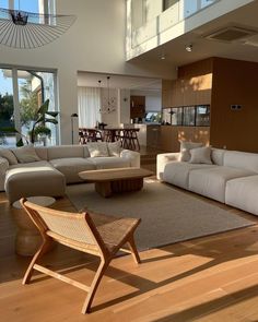 a living room filled with furniture next to a large open floor plan and lots of windows