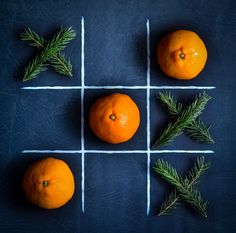 three oranges sitting on top of a tic - board