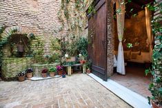 an outdoor patio with potted plants and brick walls on either side of the door