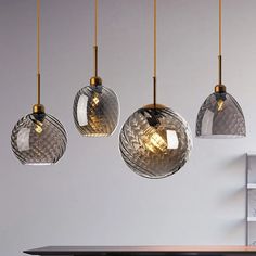 three glass pendant lights hanging from a ceiling