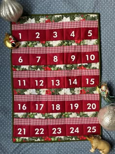 a quilted placemat with numbers and christmas decorations on it, next to ornaments