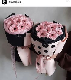 two pink flowers are wrapped in black and white polka dot paper with ribbon around them