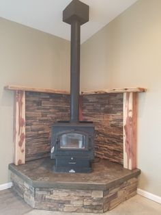 a wood burning stove sitting inside of a living room next to a stone fireplace mantel