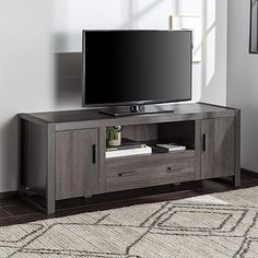 a flat screen tv sitting on top of a wooden entertainment center next to a window