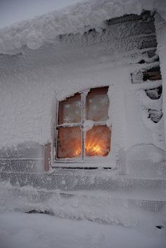 a window is covered in snow and lit by a light that shines through the window