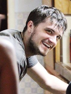 a man smiling while sitting in front of a laptop computer