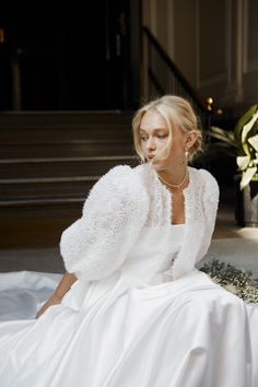 a woman sitting on the ground wearing a white dress