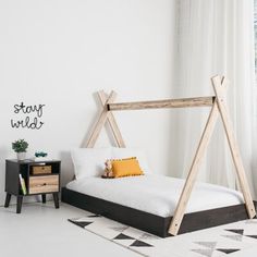 a bedroom with white walls and black accents, including a bed frame that is made out of wood