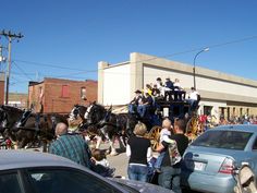 a group of people riding on the back of a horse drawn carriage down a street